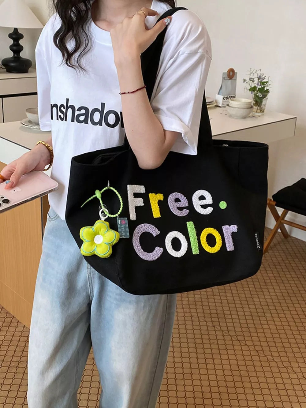 Black canvas shoulder bag with embroidered "Free. Color" text and flower charm