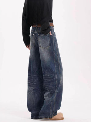 Men's vintage wide leg jeans in dark blue denim with a belted waist and distressed details.