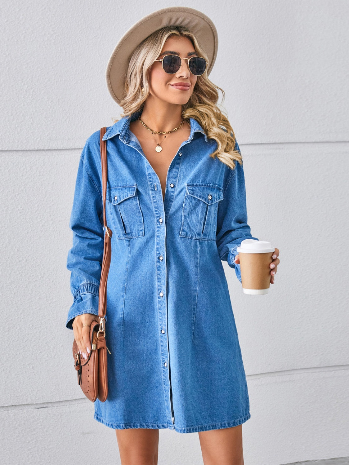 Oversized denim shirt dress in dusty blue with button front, chest pockets, and cuffed sleeves.