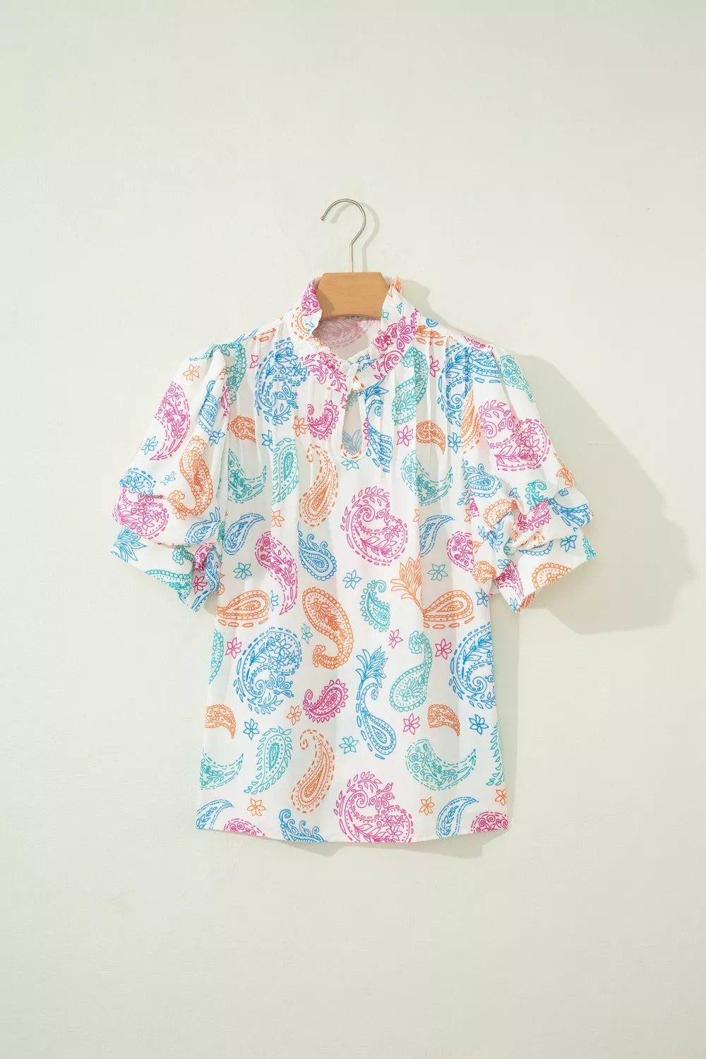 Maternity blouse with vibrant paisley print, puff sleeves, and keyhole neckline.