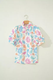 Maternity blouse with vibrant paisley print, puff sleeves, and keyhole neckline.