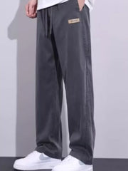 Men's grey relaxed fit sweatpants with drawstring and logo patch detail.