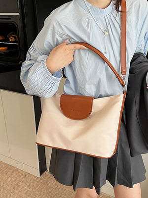 Chic canvas hobo crossbody bag in ivory with brown trim and flap.