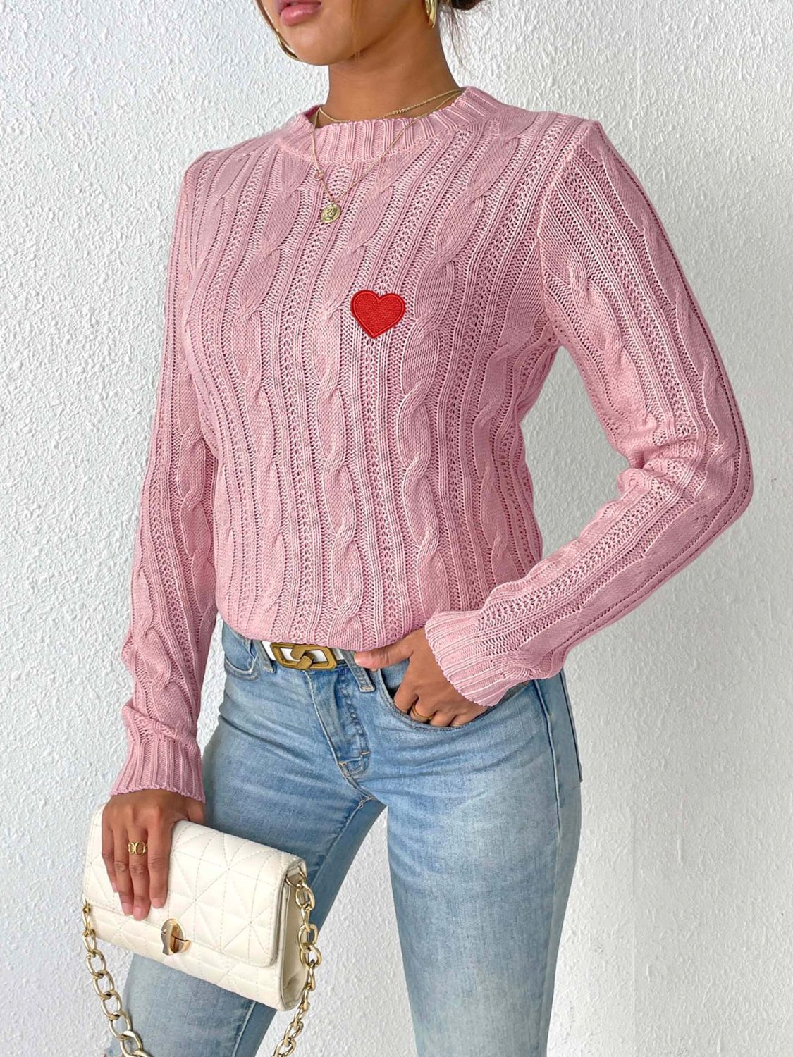 Dusty pink cable knit sweater with embroidered red heart detail.