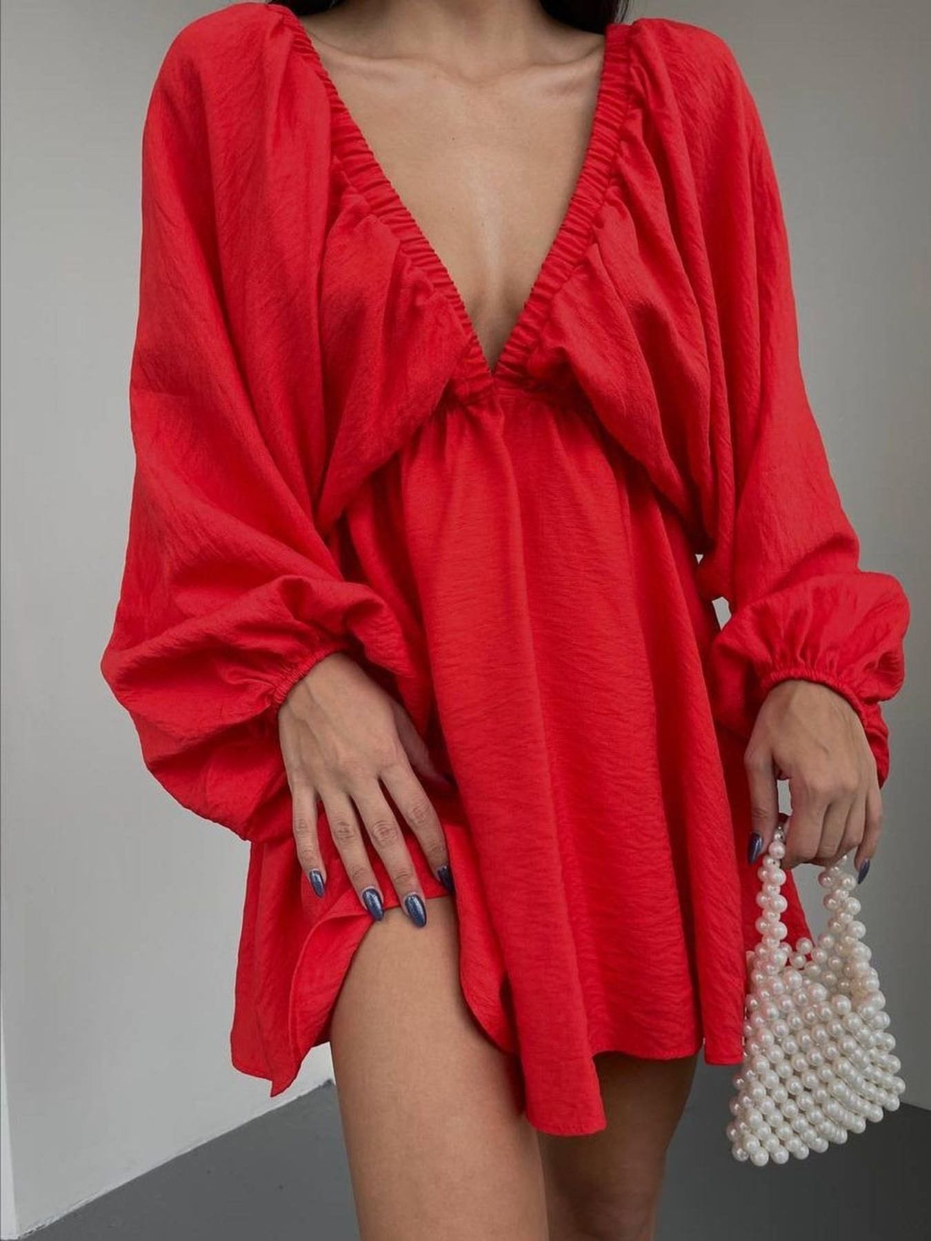 Scarlet ruched V-neck dress with balloon sleeves and a cinched waist, styled with a pearl handbag.