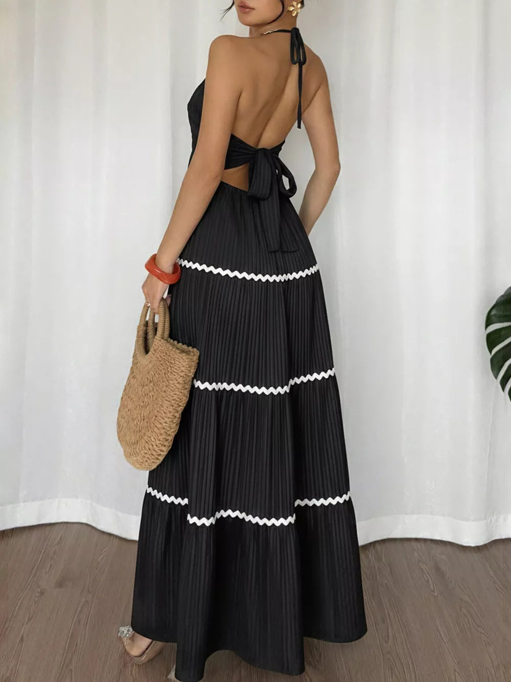 Black ruched halter maxi dress with tiered skirt and white zigzag trim.