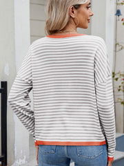 Gray and white striped knit sweater with contrast orange trim and drop shoulders.