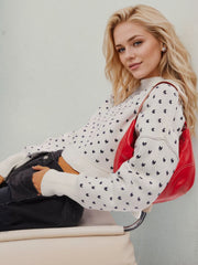 White dotted knit cropped crewneck sweater with a crew neckline and long sleeves.