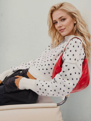 White dotted knit cropped crewneck sweater with a crew neckline and long sleeves.