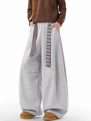 Grey wide-leg sweatpants with pockets and a striped drawstring, styled with a brown sweater.
