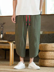 Men's army green cropped sweatpants with red drawstring detail and wide leg.