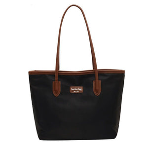Large black Oxford cloth tote bag with brown trim and handles.