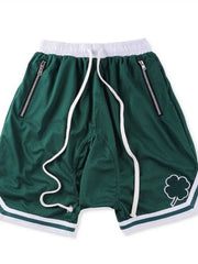Dark green mesh basketball shorts with white drawstring, zipper pockets, and clover logo detail.