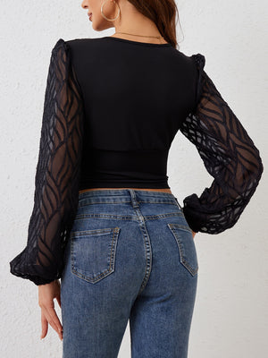 Black blouse with sheer ruched sleeves and textured pattern