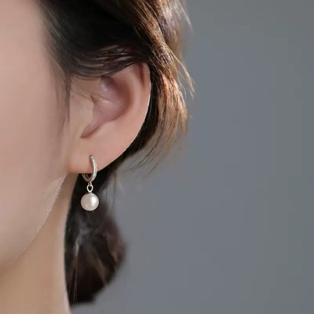 Elegant pearl drop hoop earrings with a delicate pearl and crystal accents.