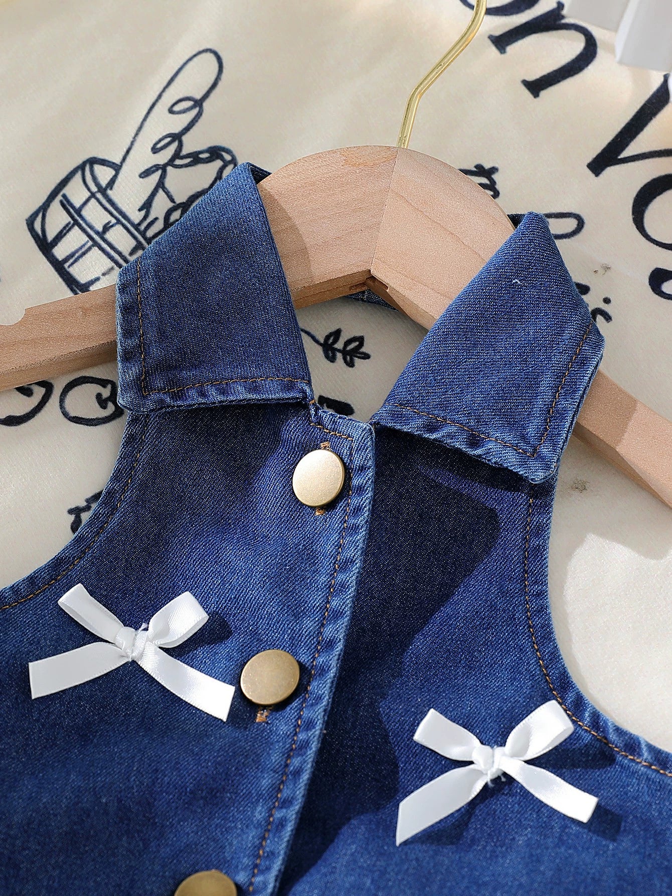 Denim halter top with white bow accents and gold buttons