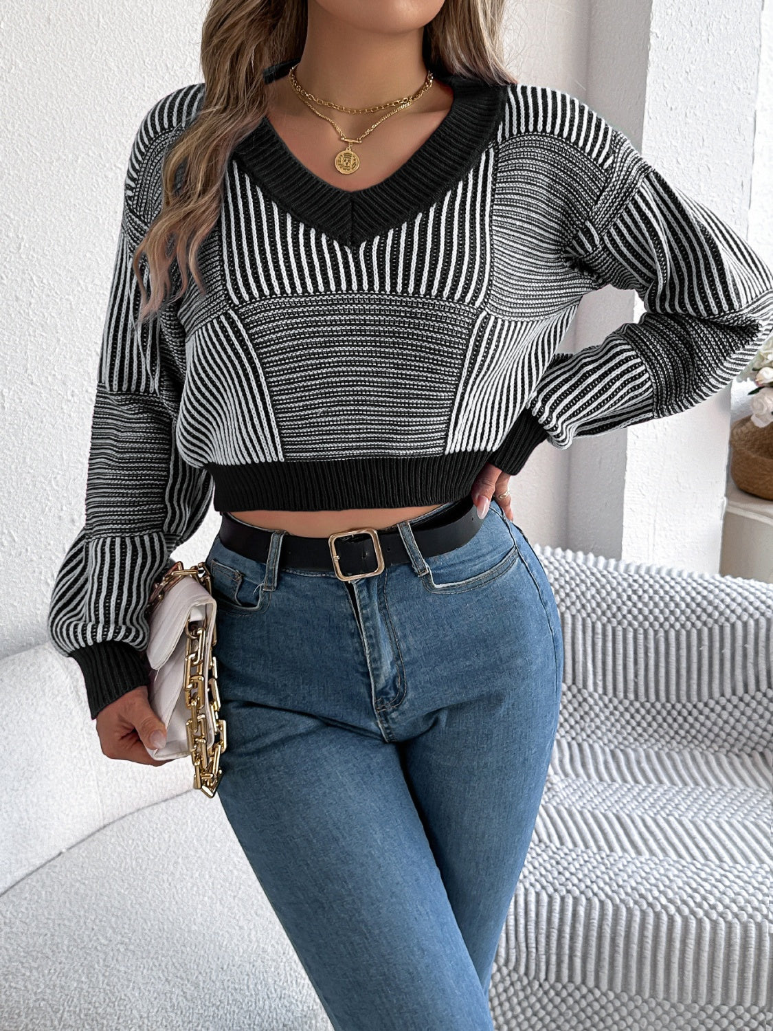 Geometric stripe cropped knit sweater with V-neck and long sleeves in black and white.