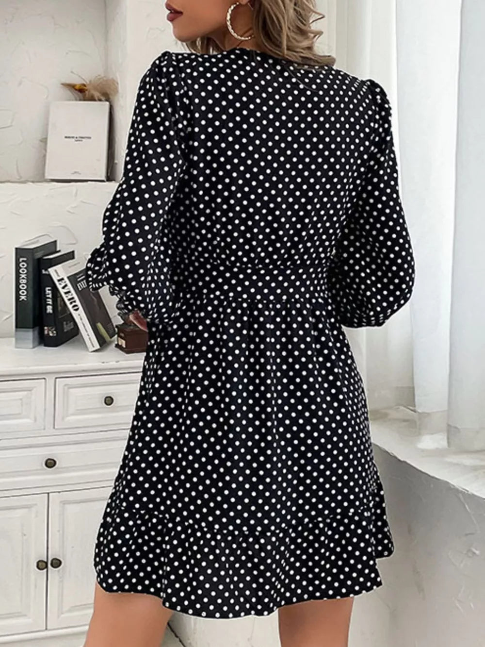 Black polka dot mini dress with balloon sleeves and ruffled hem.