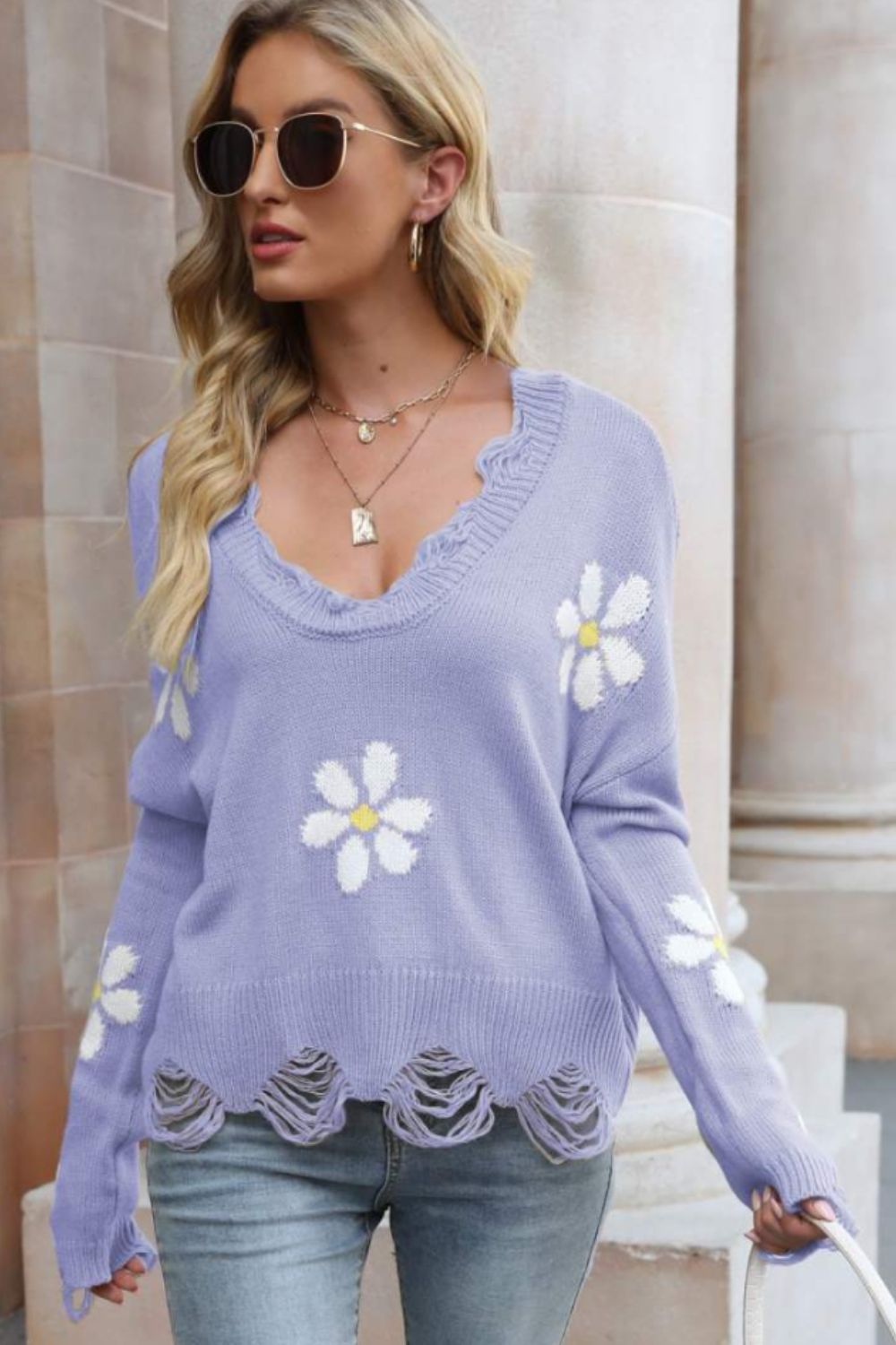 Purple distressed knit sweater with daisy appliques and frayed hem.