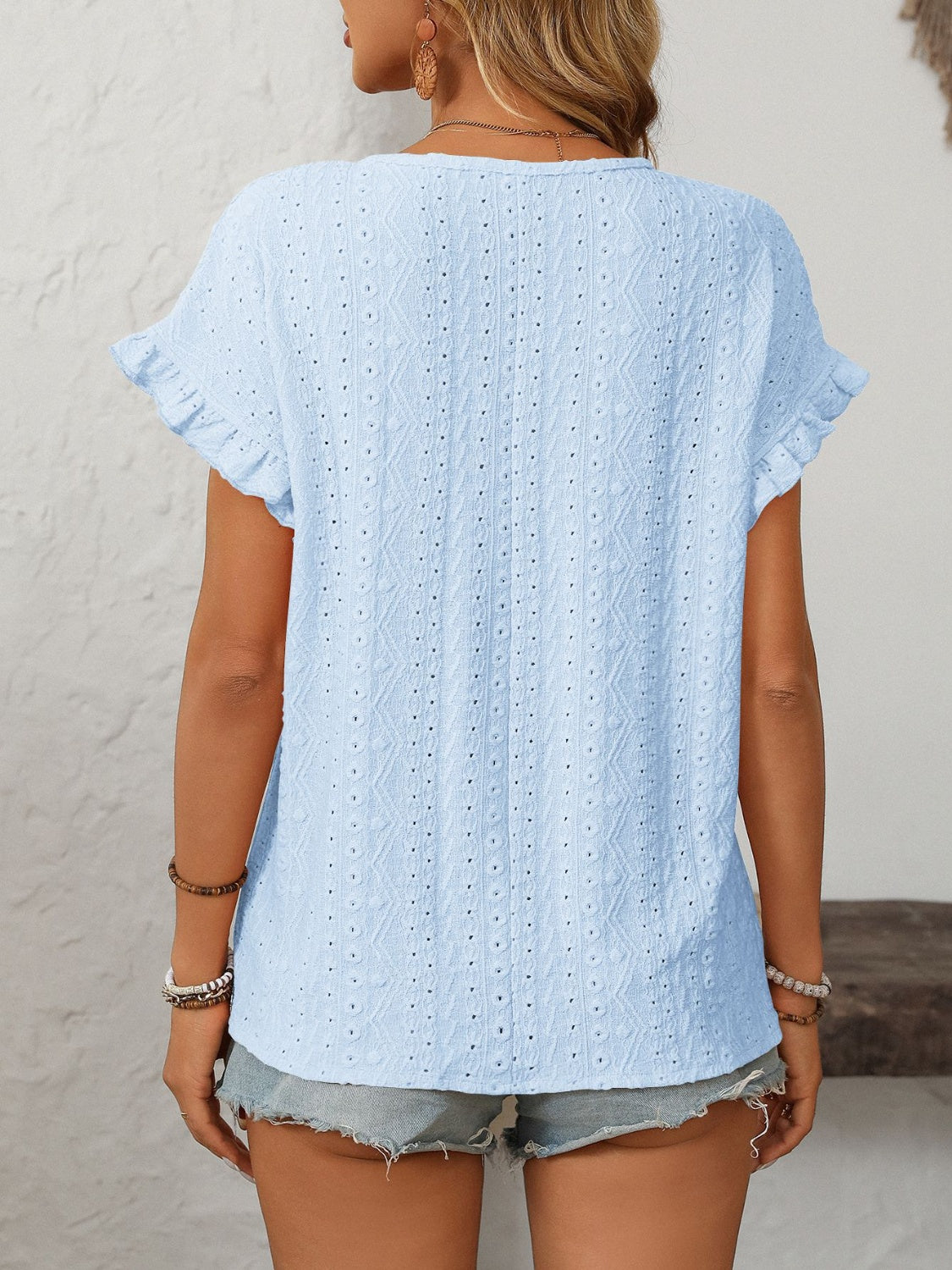 Light blue eyelet knit blouse with ruffled short sleeves and a textured pattern.