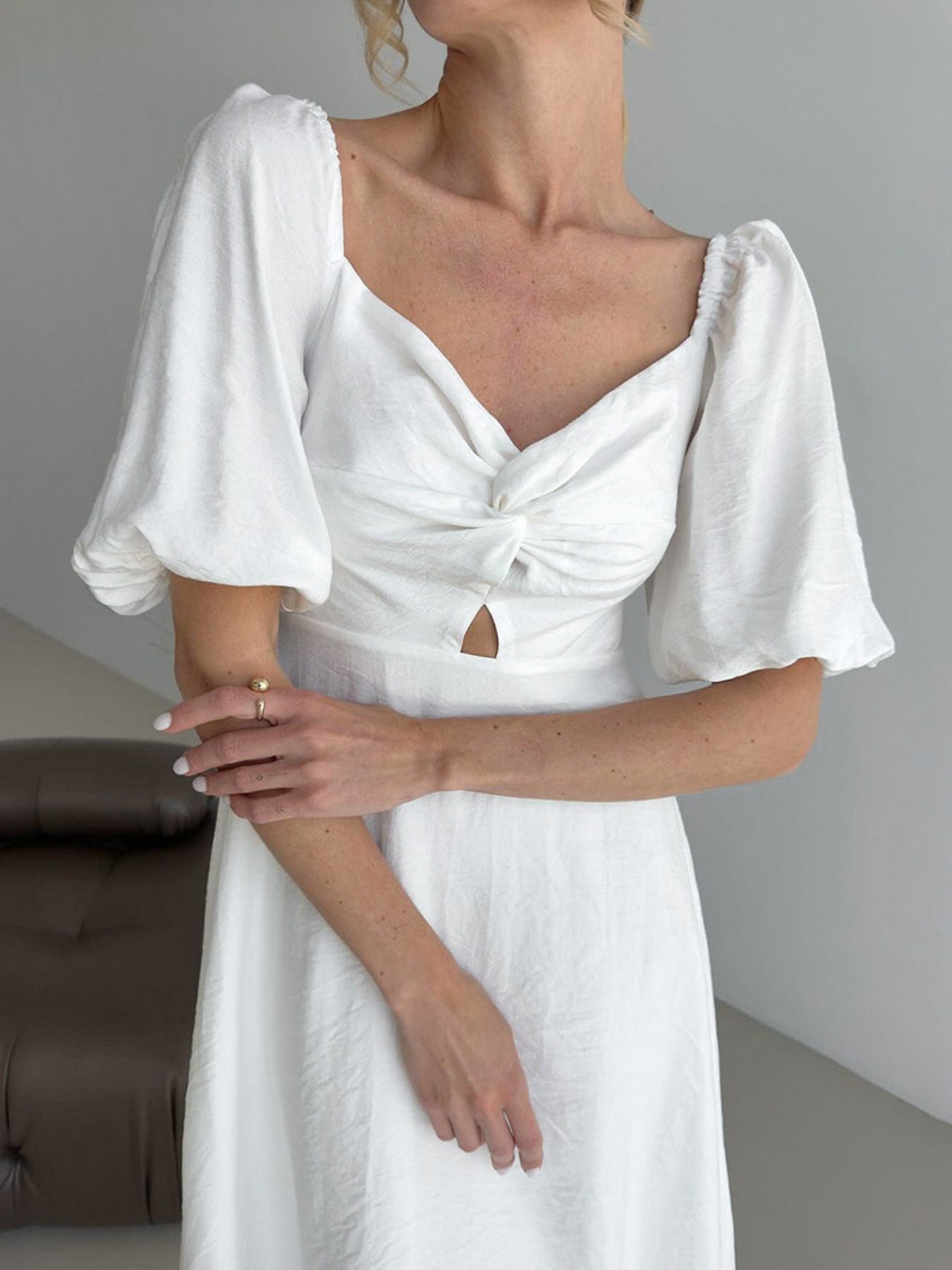 White midi dress with off-shoulder neckline, twisted bust, cutout detail, and puff sleeves.