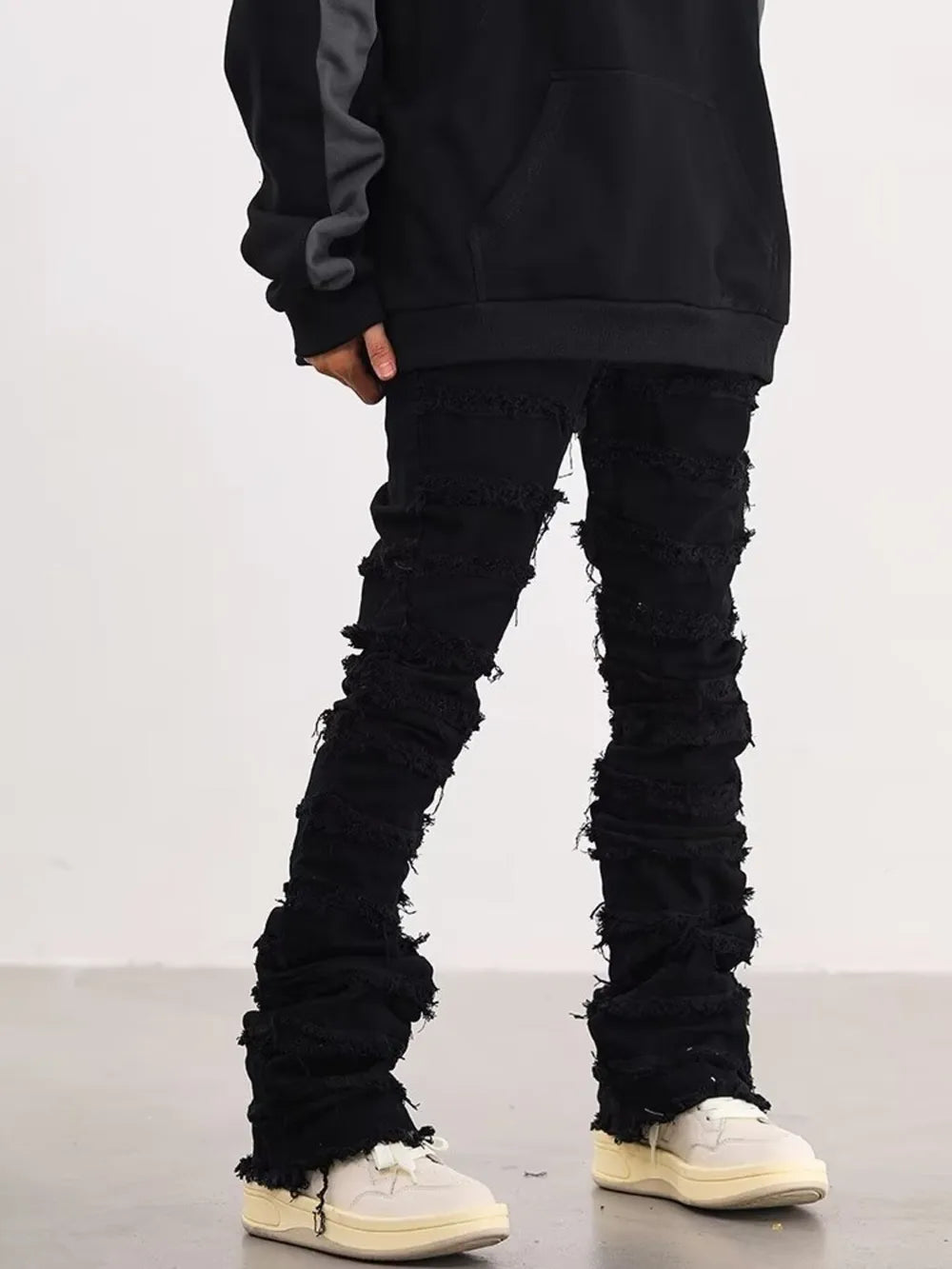 Black cotton jeans for men with frayed hem and distressed details.
