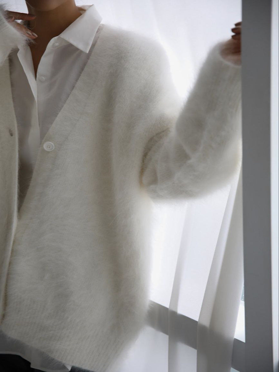 White angora buttoned cardigan with sculpted sleeves over a white collared shirt.