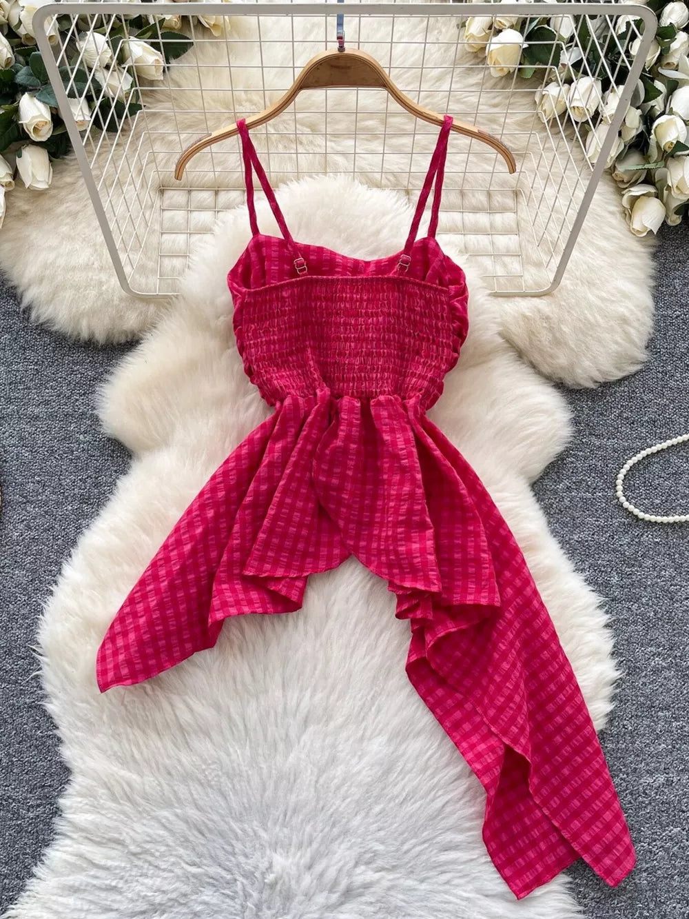 Rose red cami top with smocked bodice and asymmetrical ruffled hem.