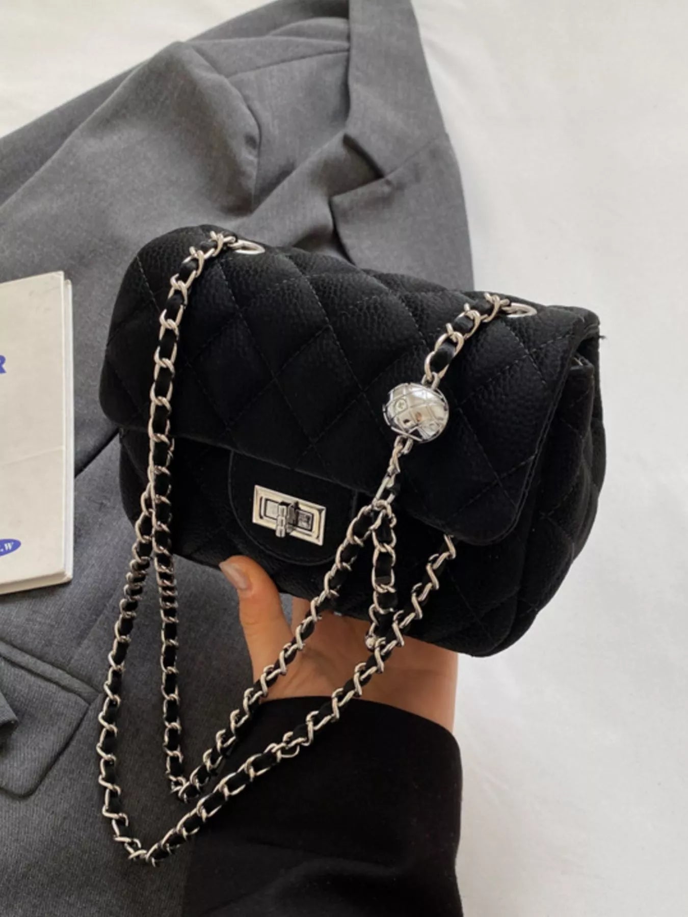 Black quilted chain crossbody clutch with silver hardware and decorative ball detail.