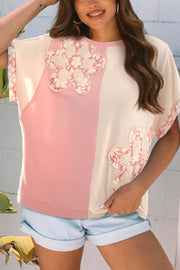 Maternity t-shirt with color block design, applique flowers, and short sleeves.