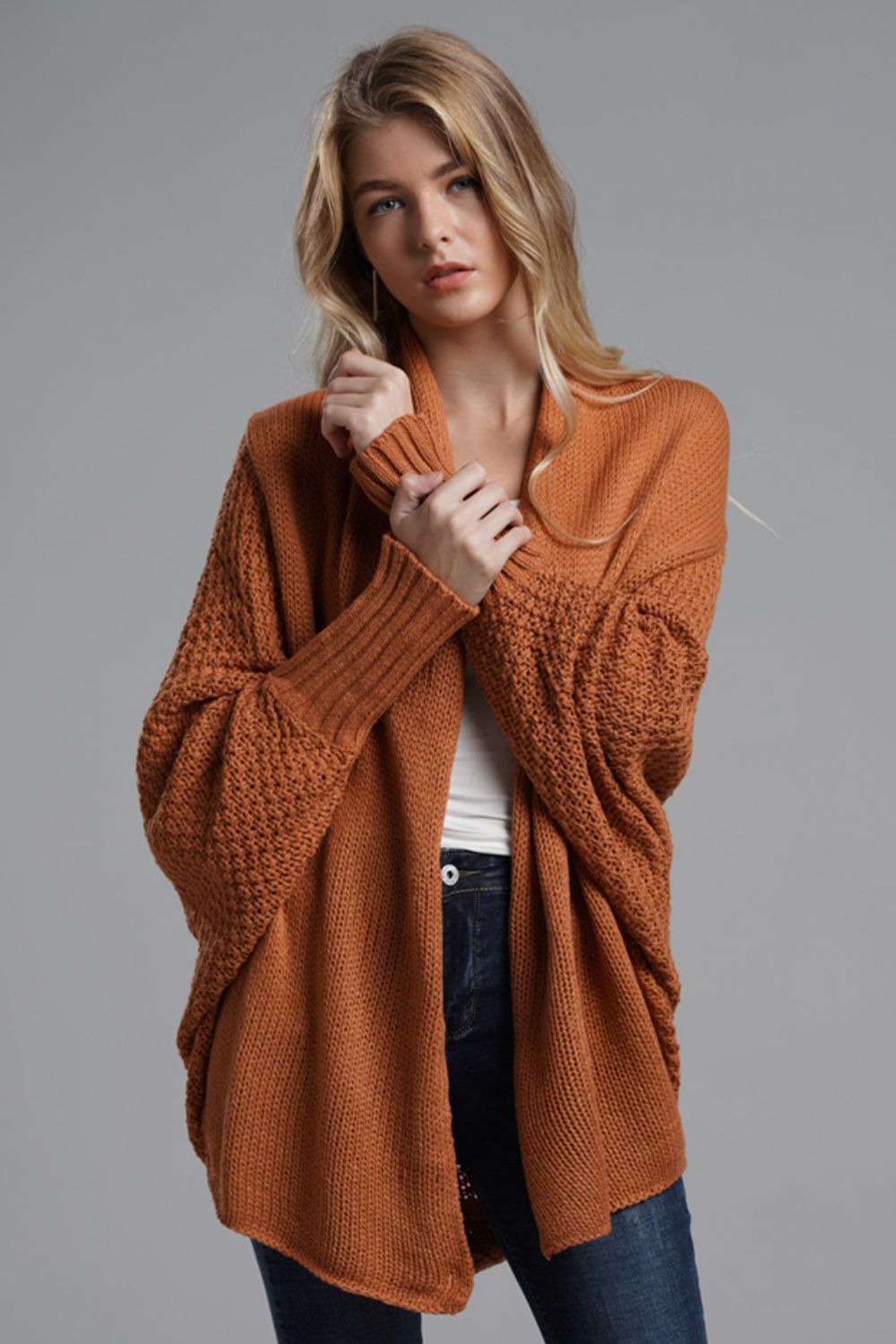 Drape-front batwing knit cardigan in rust orange with textured sleeves and ribbed cuffs.