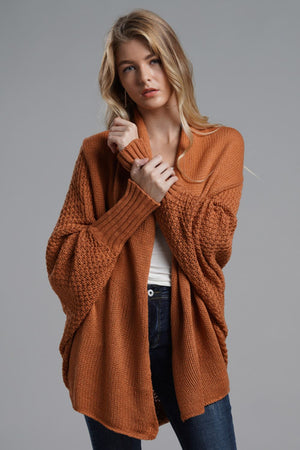 Drape-front batwing knit cardigan in rust orange with textured sleeves and ribbed cuffs.