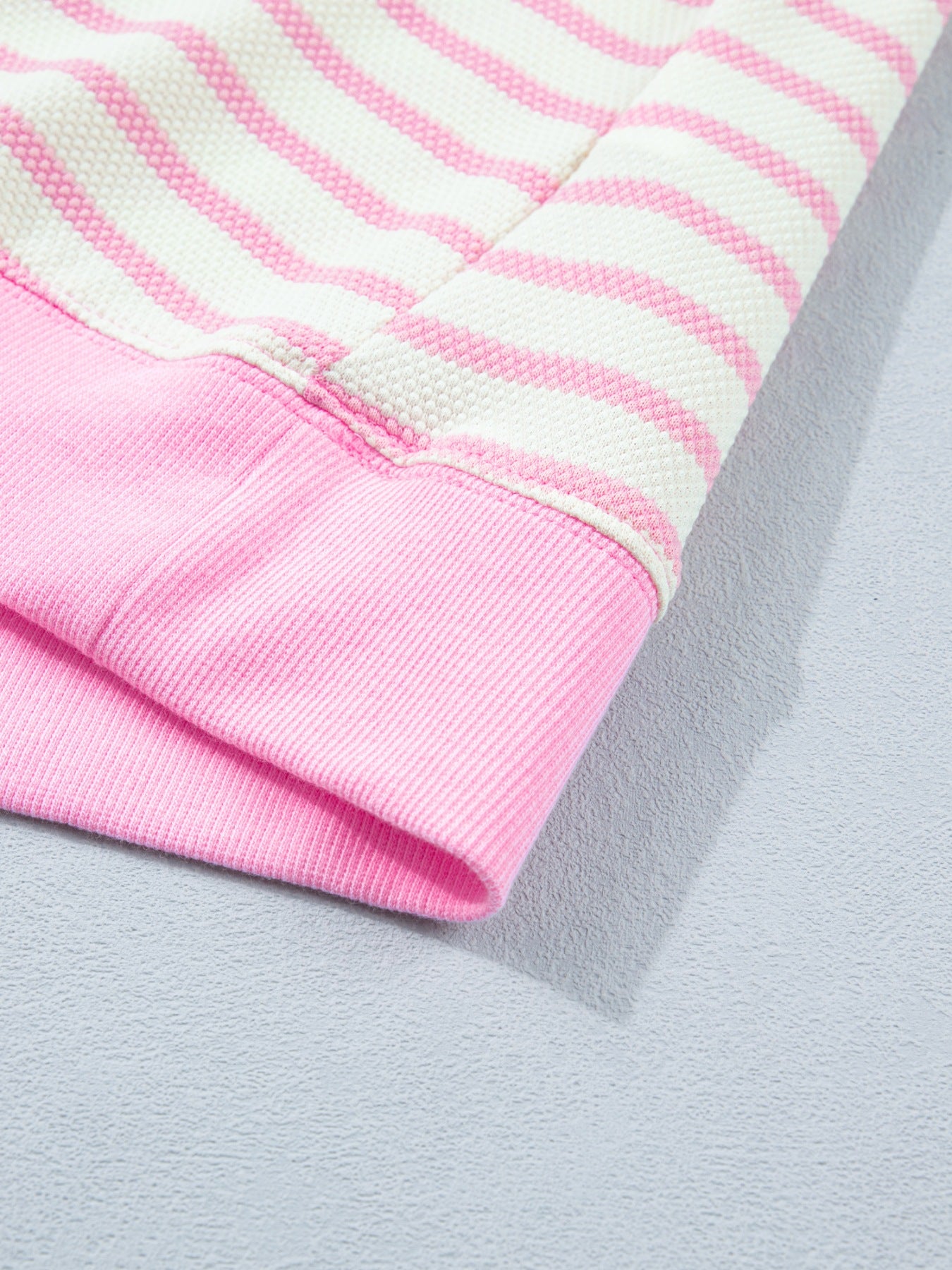Ruffled short-sleeve blouse in pink and white stripes with a pink ribbed cuff detail.