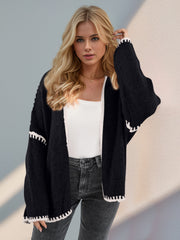 Black oversized knit cardigan with contrast white stitching detail on cuffs and hem.