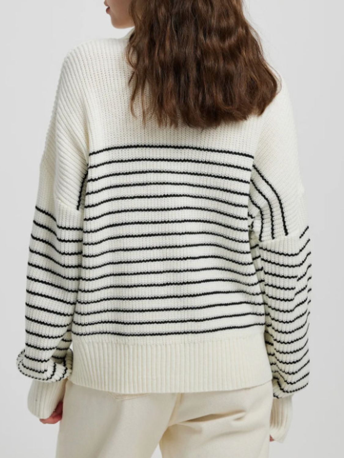 Cream ribbed knit sweater with black horizontal stripes and a half-zip neckline.