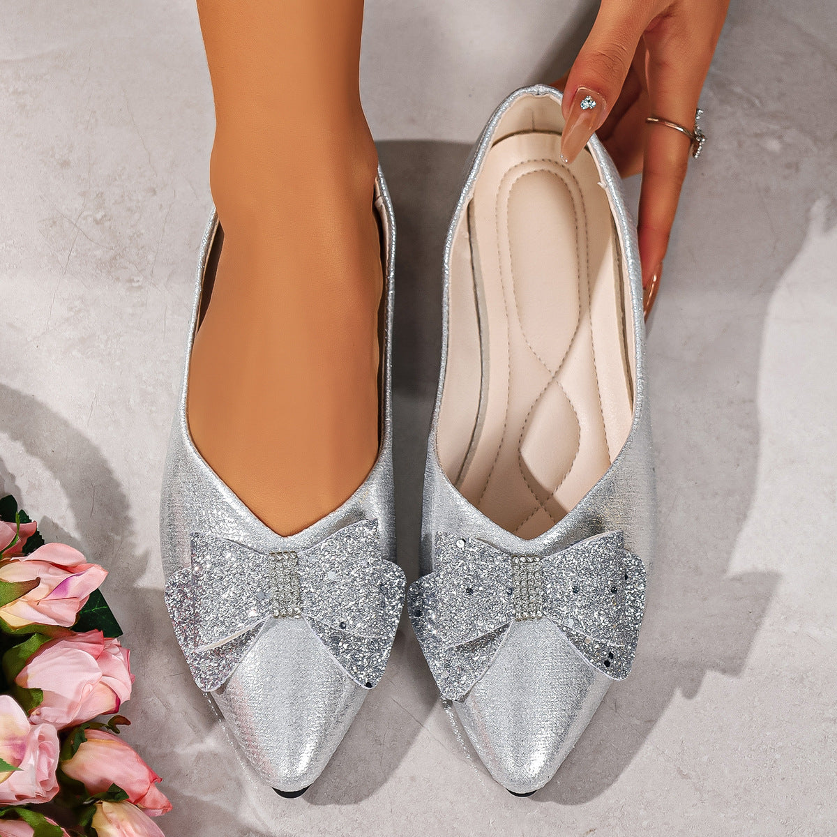 Silver pointed toe flats with glitter bows and rhinestone accents.