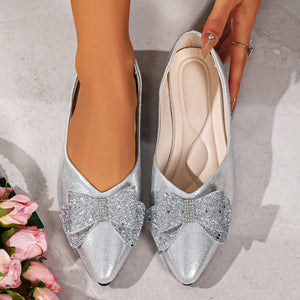 Silver pointed toe flats with glitter bows and rhinestone accents.