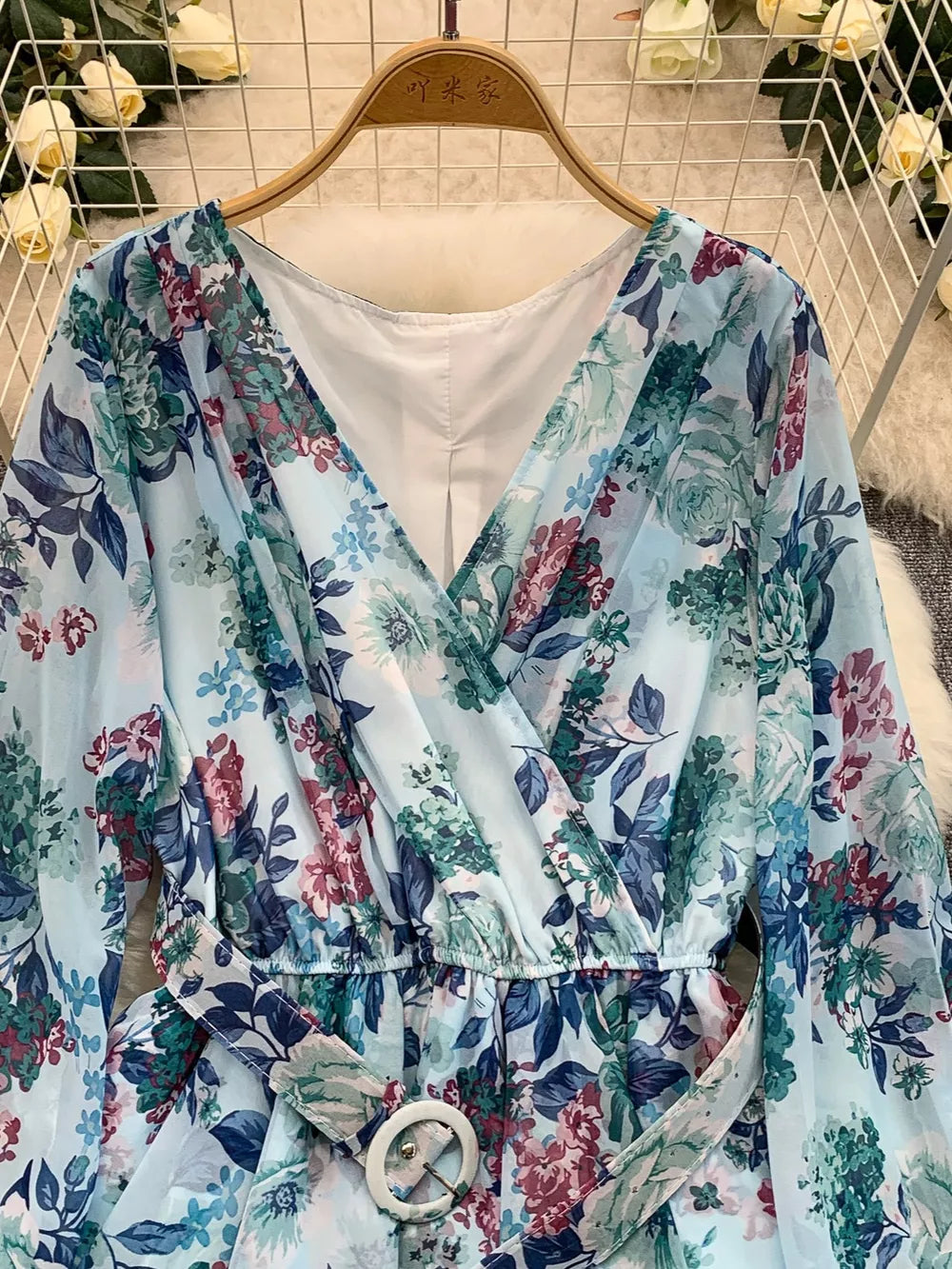 Light blue floral wrap mini dress with V-neck, cinched waist, and belt.