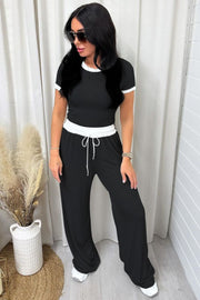 Black ribbed lounge set with white contrast trim on neckline and waistband, wide leg pants with drawstring.