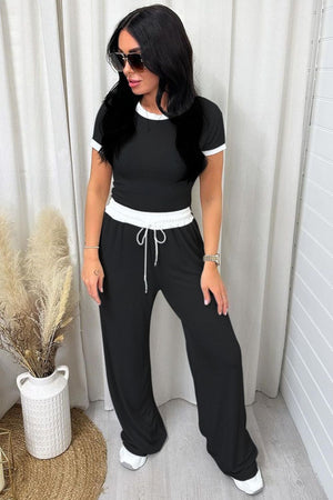Black ribbed lounge set with white contrast trim on neckline and waistband, wide leg pants with drawstring.
