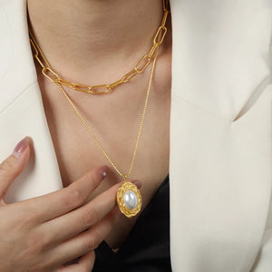 Gold double-layered necklace with oval pearl pendant and paperclip chain.