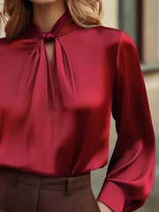 Red satin blouse with a tie-neck and cutout detail.