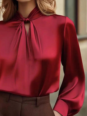 Red satin blouse with a tie-neck and cutout detail.