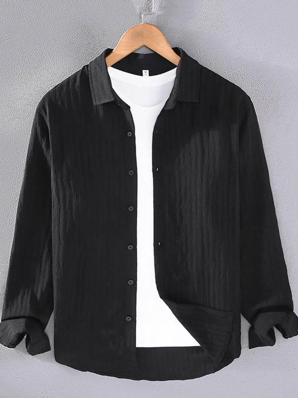 Black textured long sleeve button-up overshirt with classic collar, worn over a white t-shirt.