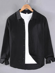 Black textured long sleeve button-up overshirt with classic collar, worn over a white t-shirt.