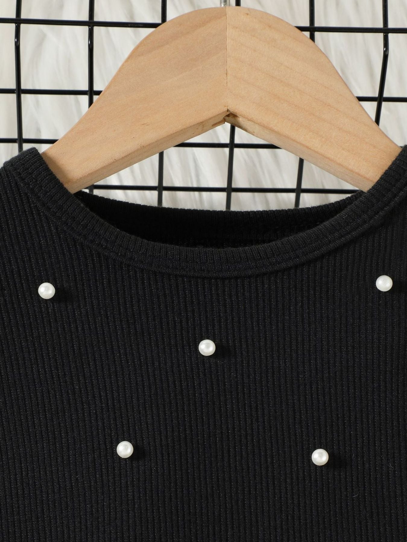 Black toddler top with pearl embellishments and ribbed texture.