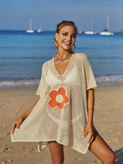 Cream crochet beach cover-up with orange daisy appliqué and V-neck.