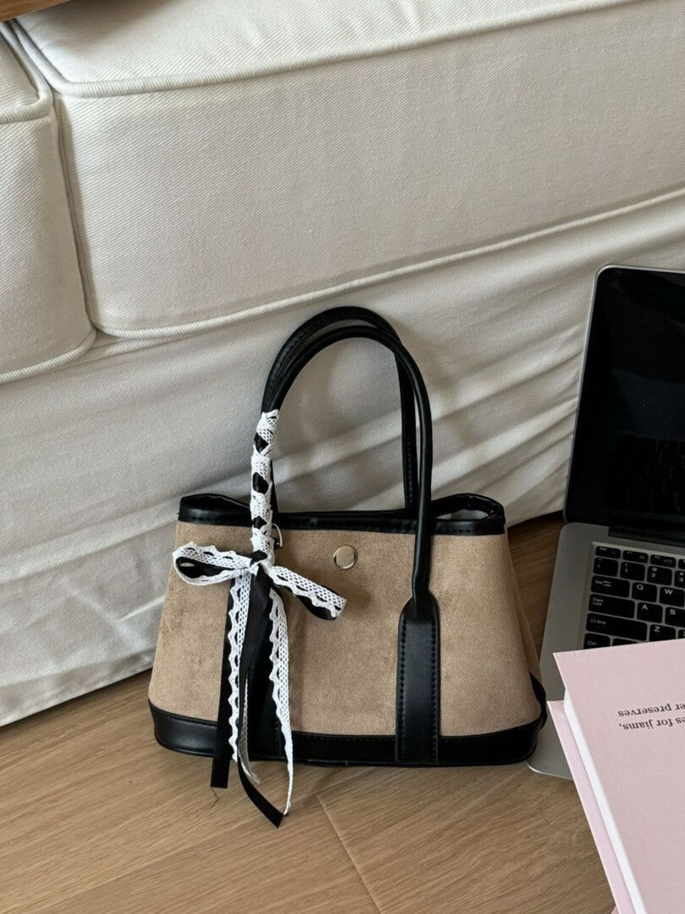 Tan tote bag with black trim and lace-trimmed ribbon detail