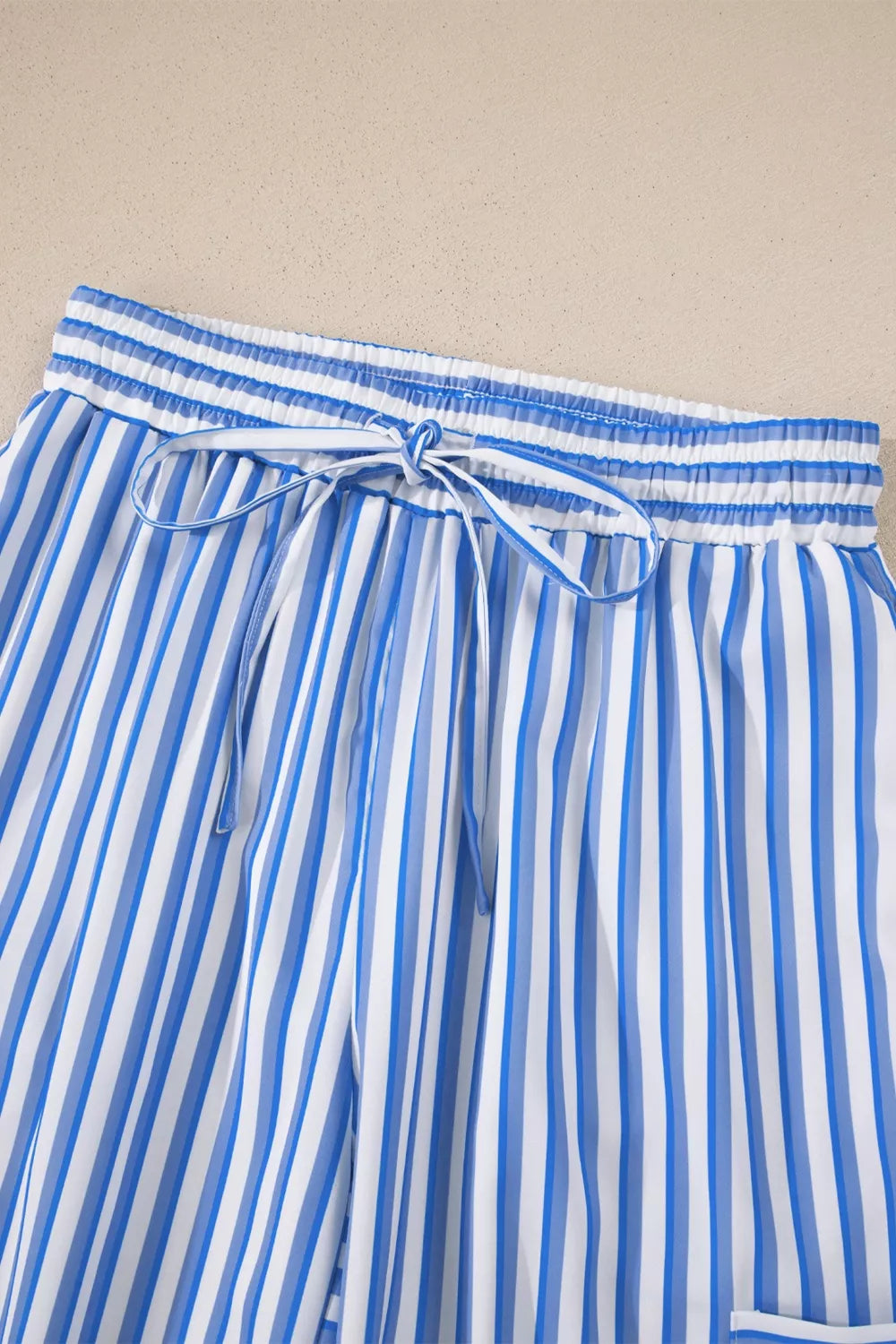 Maternity pants with blue and white vertical stripes, drawstring waist, and pockets.