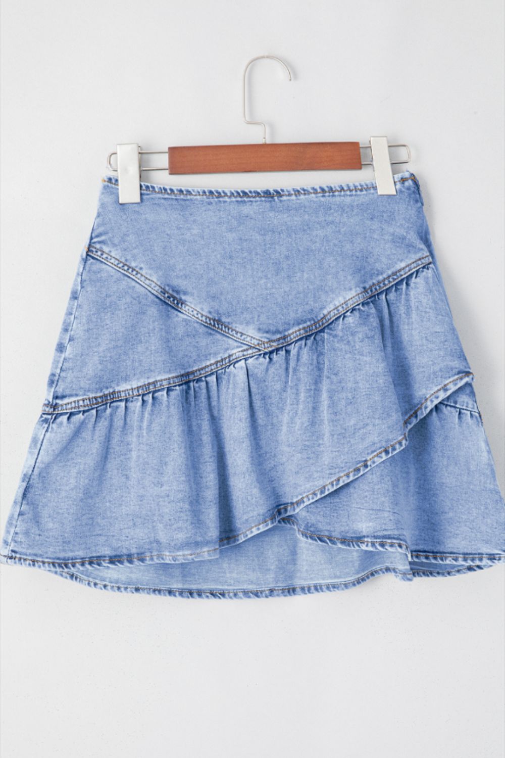 Asymmetrical denim ruffle mini skirt in medium wash cotton with tiered ruffles.